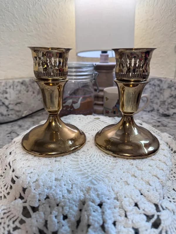 A pair of vintage brass candlestick holders on a lace doily